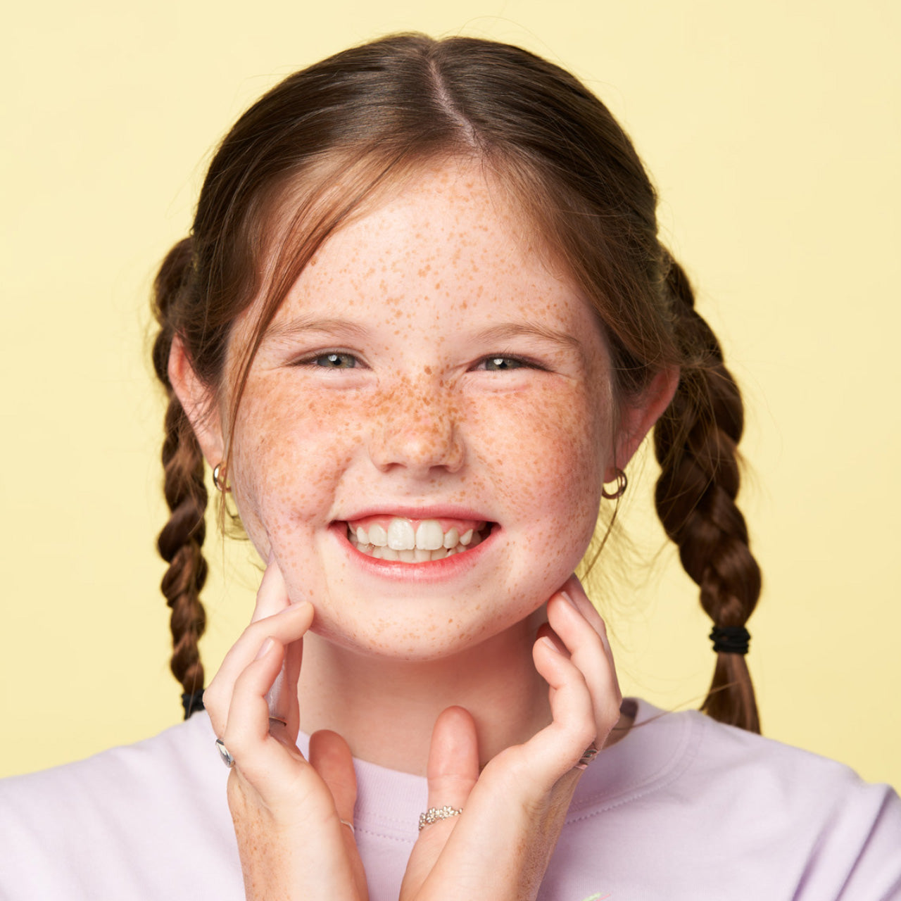 Child with freckles and braids smiling at camera